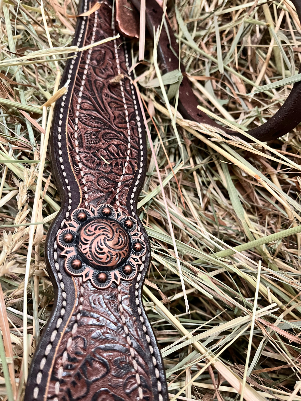 Poitrail western Weaver Equine en cuir anglais Havana, décoré d'un overlay floral marron et d'éléments floraux en finition cuivre antique, en situations dans du foin, tooling et conchos